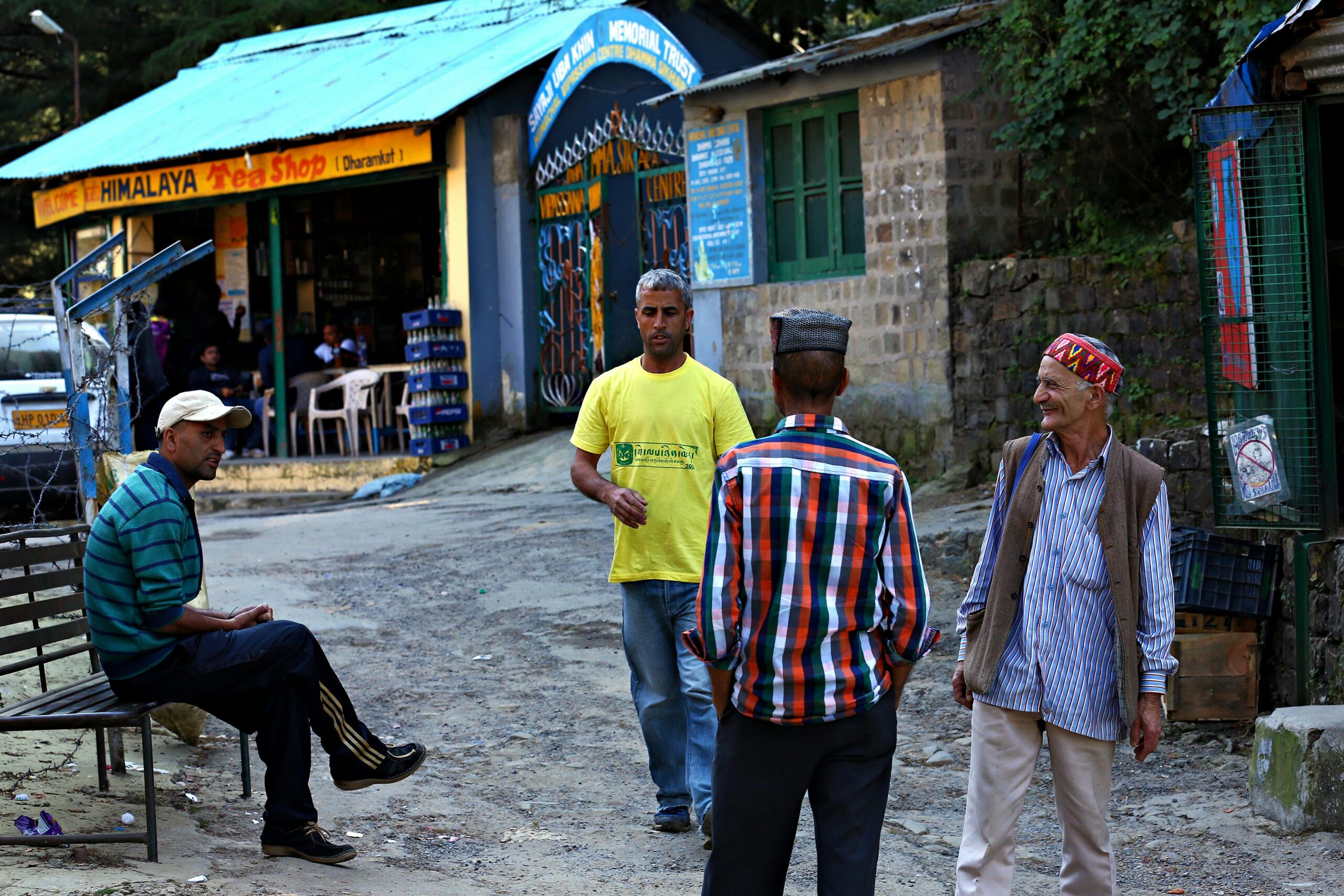 Casual street scene outside a Himalayan tea shop in Dharamkot, India. People gather and converse.